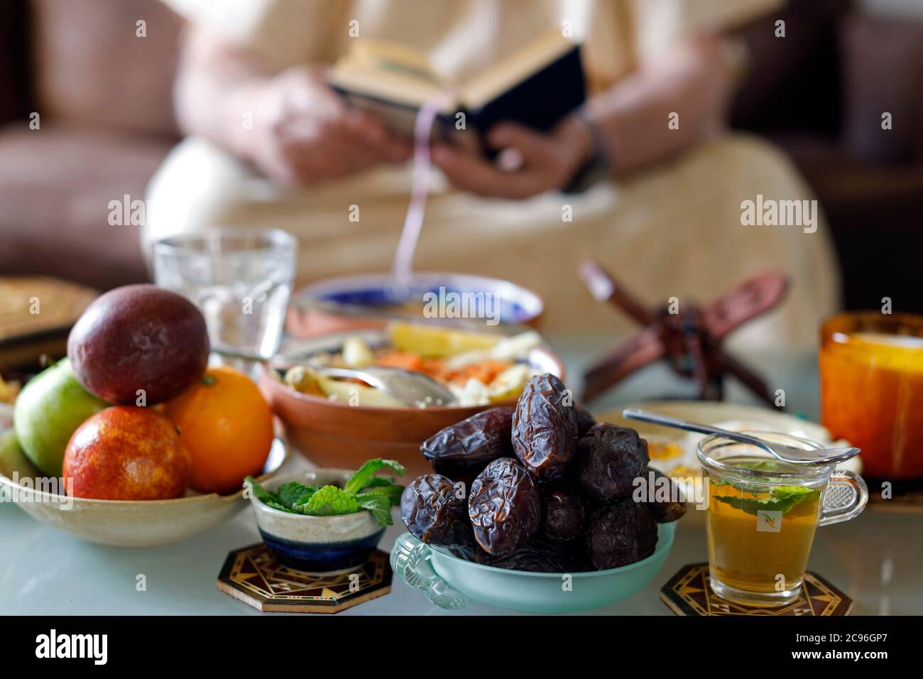 Traditional meal for iftar in time of Ramadan after the fast has been broken.  Muslim reading Quran.  France. Stock Photo