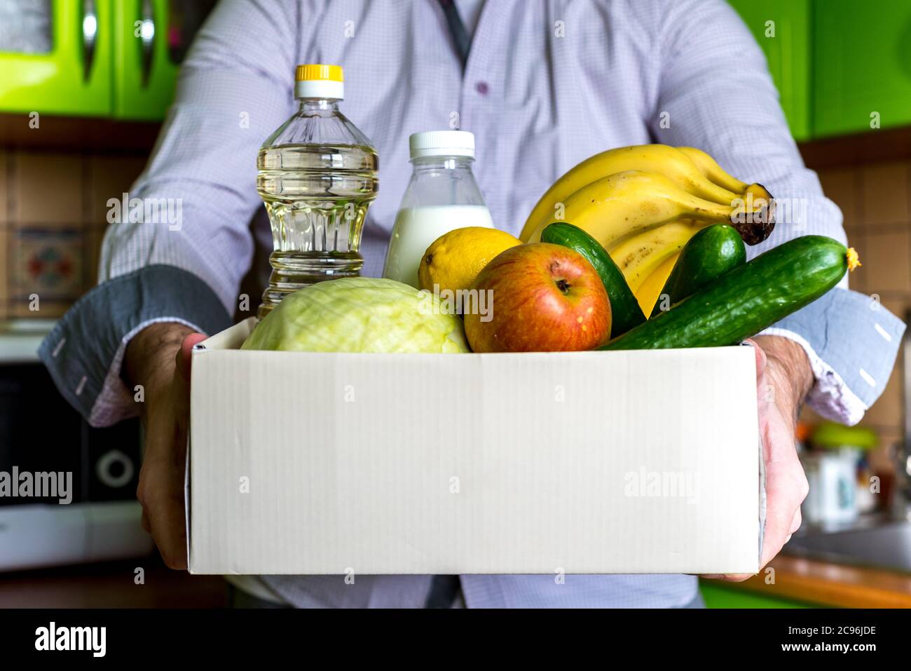Donation box food delivery Food donation concept. A man holding a donation box with vegetables, fruits and other food for people Stock Photo