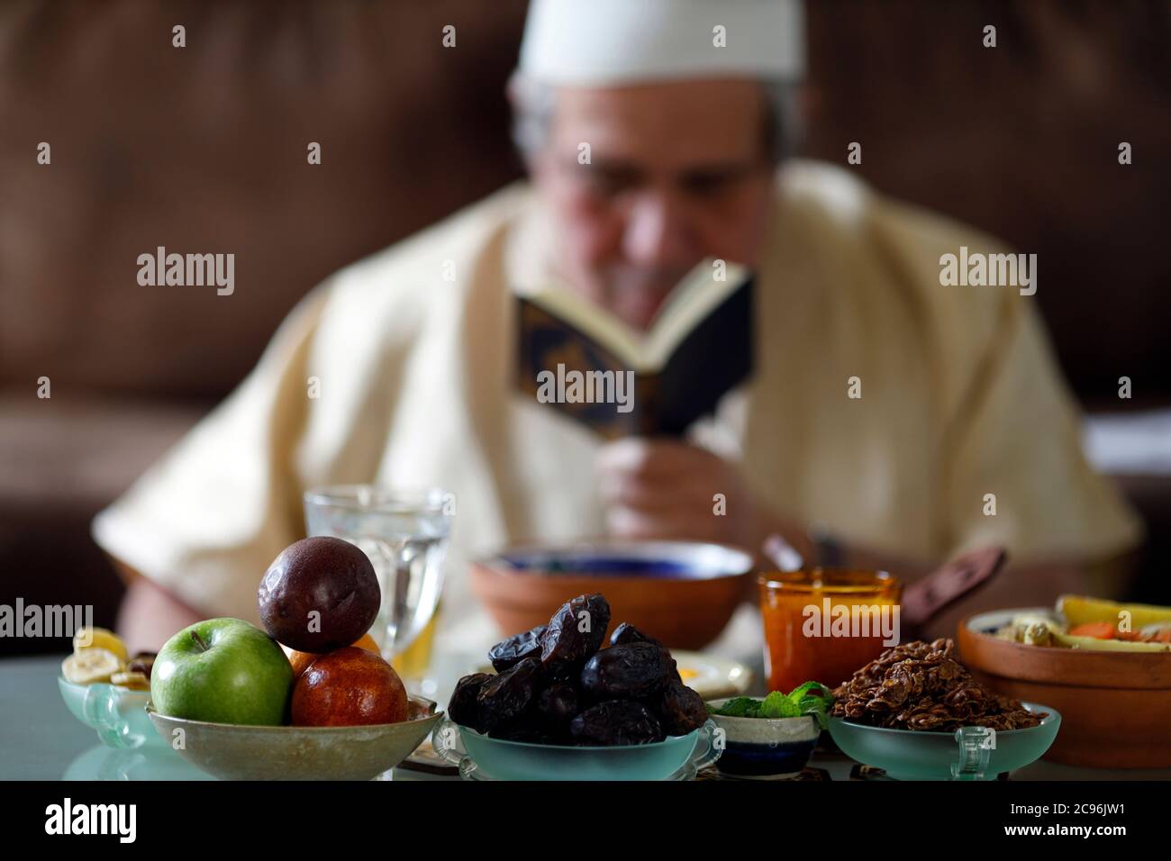 Traditional meal for iftar in time of Ramadan after the fast has been broken.  Muslim reading Quran.  France. Stock Photo