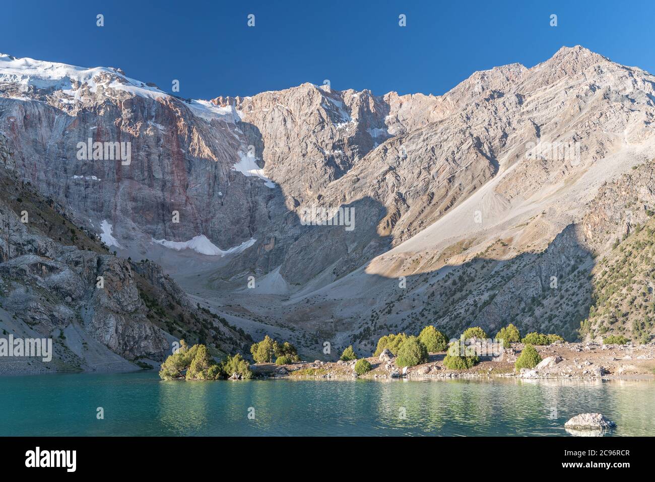 The Pamir range view and peaceful campsite on Kulikalon lake in Fann mountains in Tajikistan. Amasing colorful reflection in pure ice lake. Stock Photo