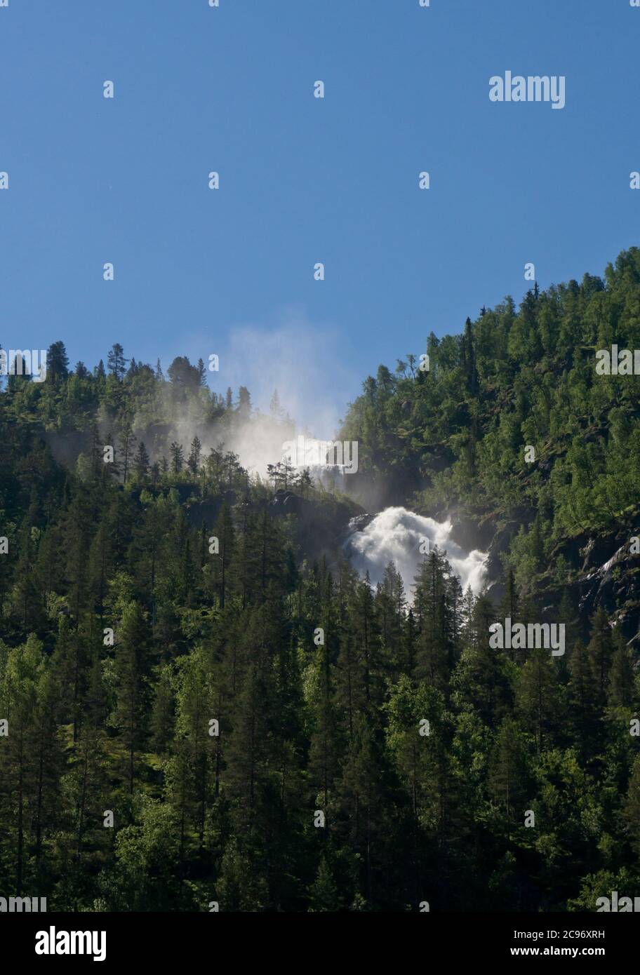 Waterfall foaming and cascading down a mountainside in the mountains of Telemark in southern Norway Stock Photo