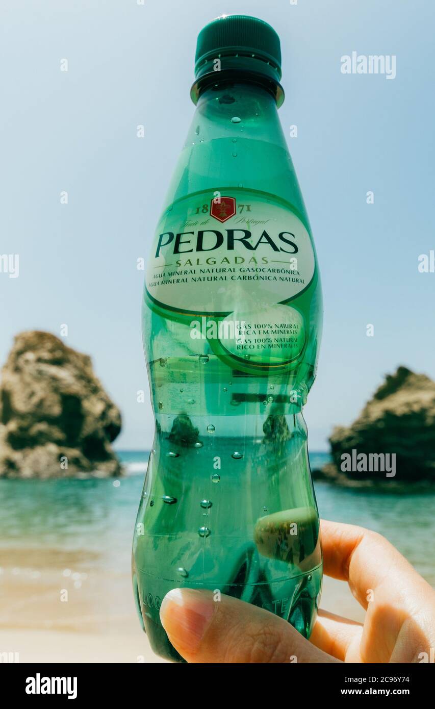 Illustrative editorial of Aguas das Pedras sparkling water bottle on a beach Stock Photo