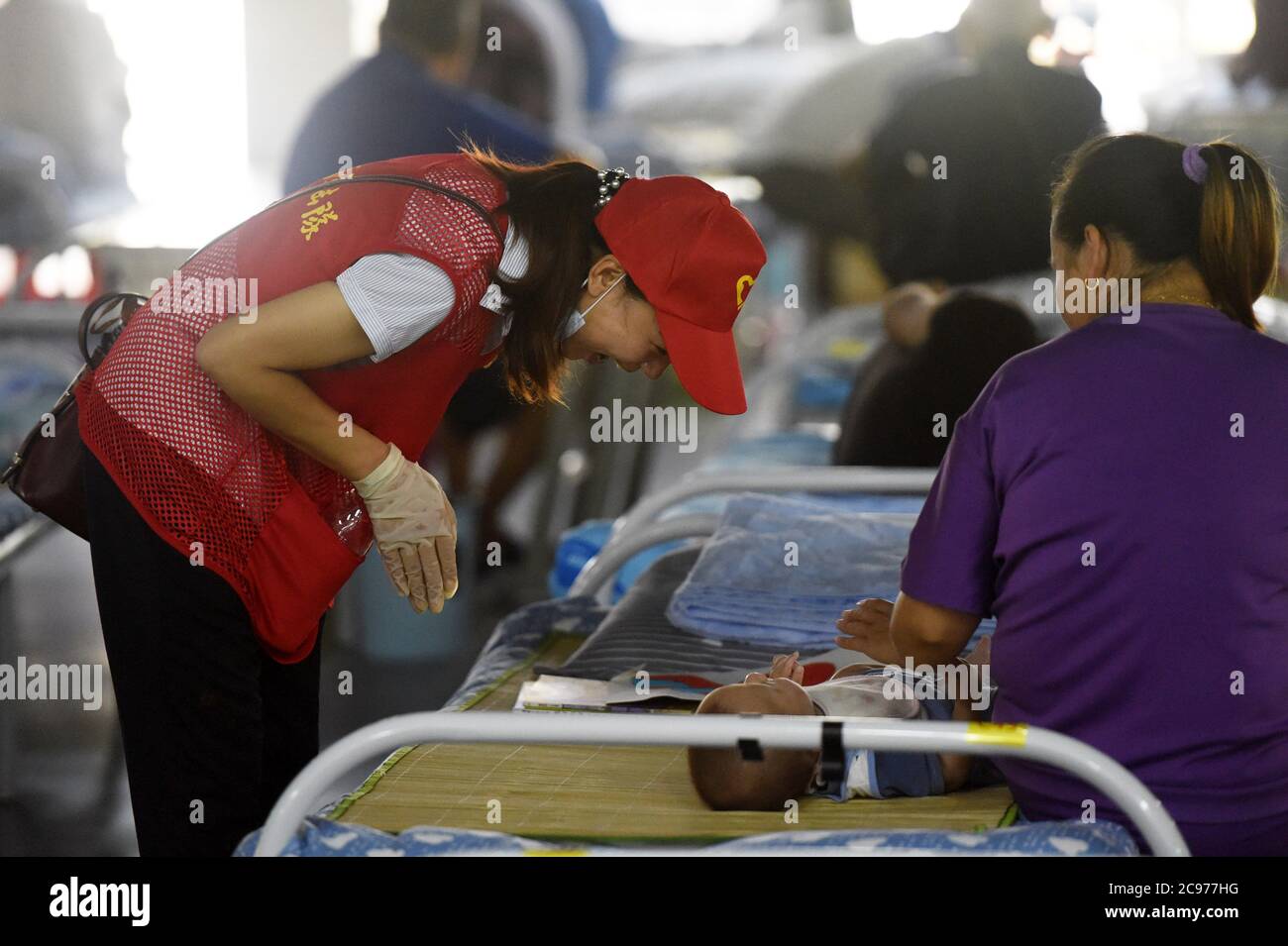 Hefei, China's Anhui Province. 29th July, 2020. A volunteer interacts with a child at a temporary shelter in the No.168 Middle School in Hefei, east China's Anhui Province, July 29, 2020. Affected by floods, more than 300 villagers in Sanhe Town of Hefei were transferred to the school. Free meals, psychological counseling and daily living assistance are provided in the shelter. Credit: Zhou Mu/Xinhua/Alamy Live News Stock Photo