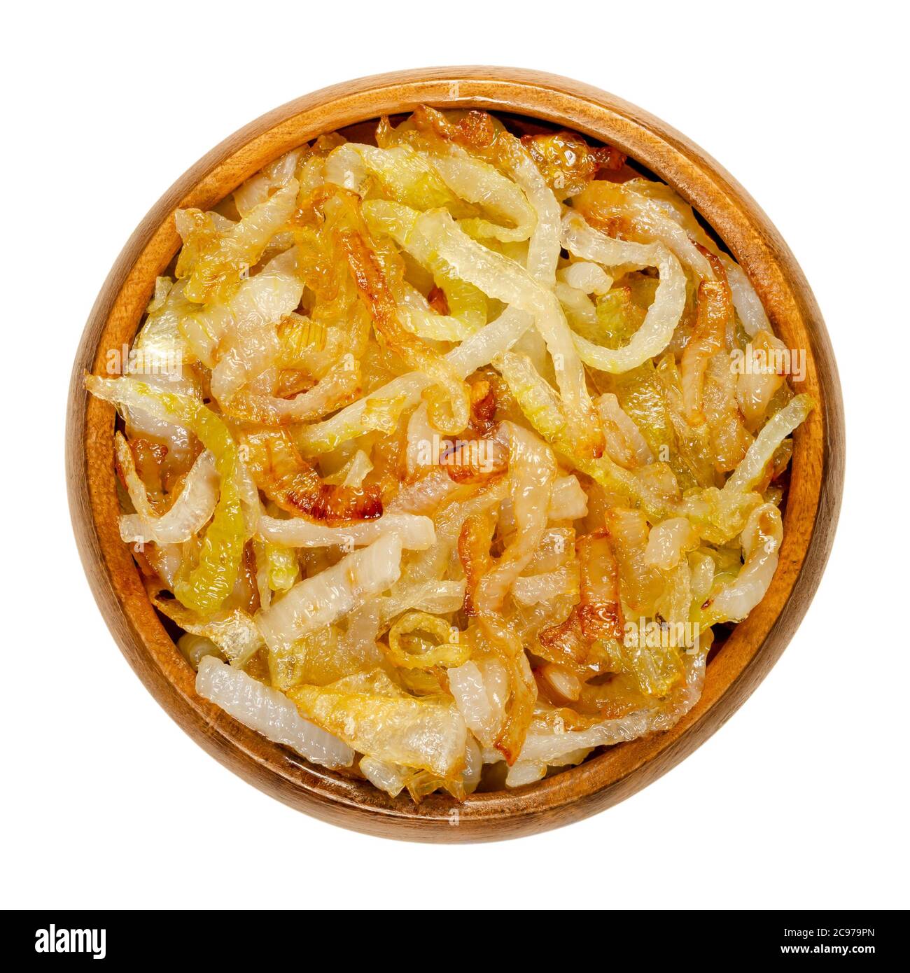 Onions, golden brown roasted, in a wooden bowl. Sliced white onions, fried in oil to get a nice color and fully aroma. Allium cepa. Closeup from above Stock Photo
