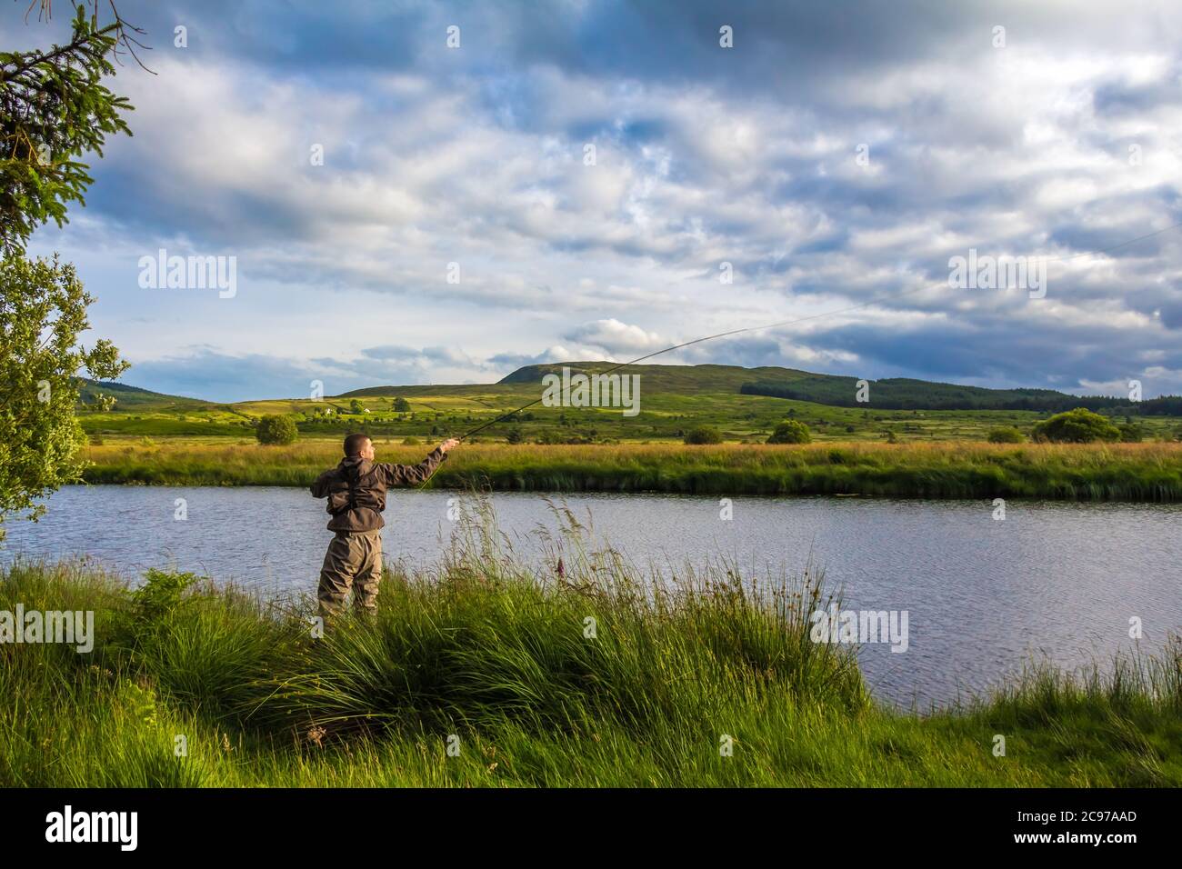 A fisherman fly fishing in the evening sun on the Blackwater of Dee, Galloway, Scotland Stock Photo