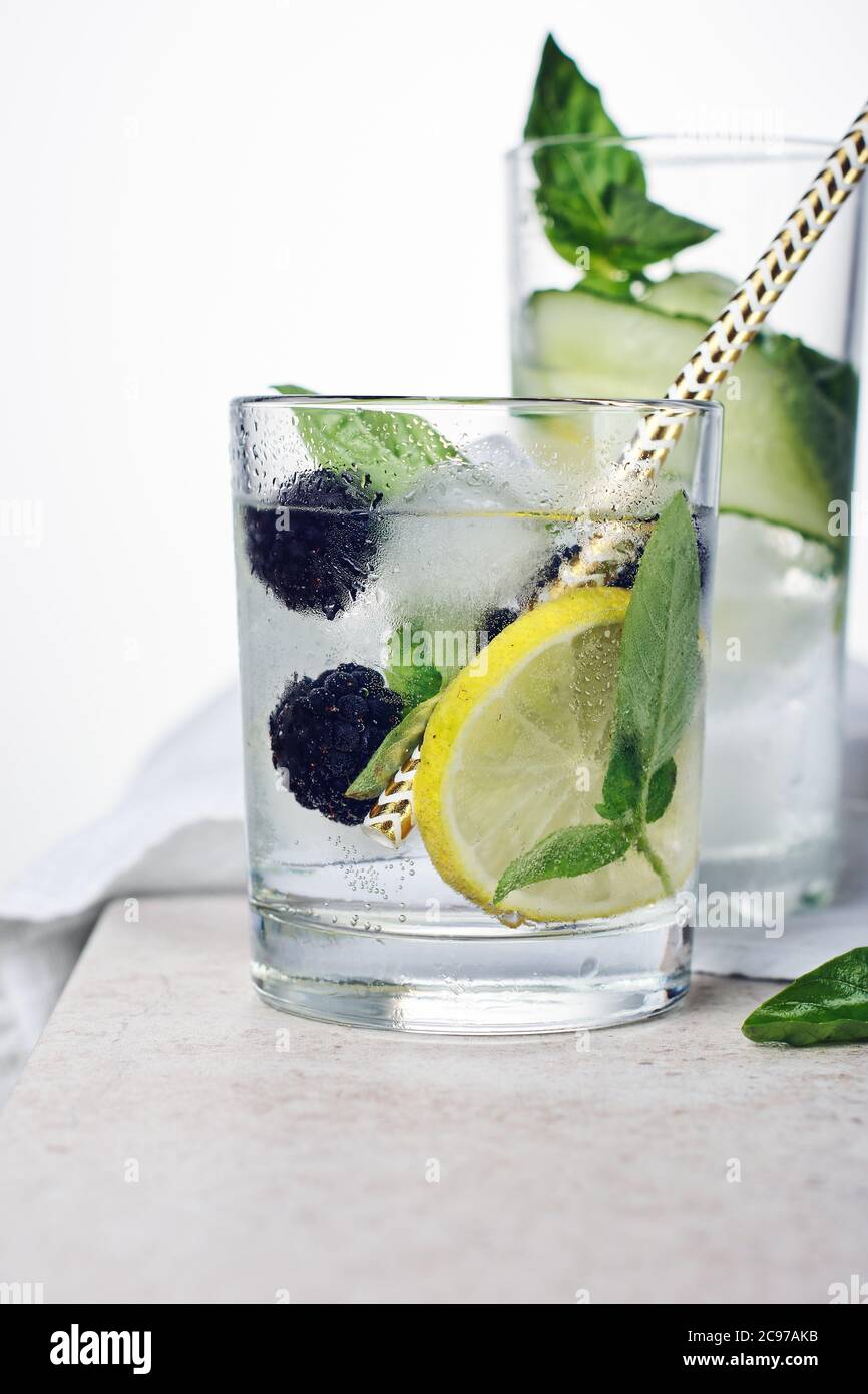 Summer refreshing drink, tonic with lemon, blackberry, cucumber and basil leaves on a light background. Stock Photo