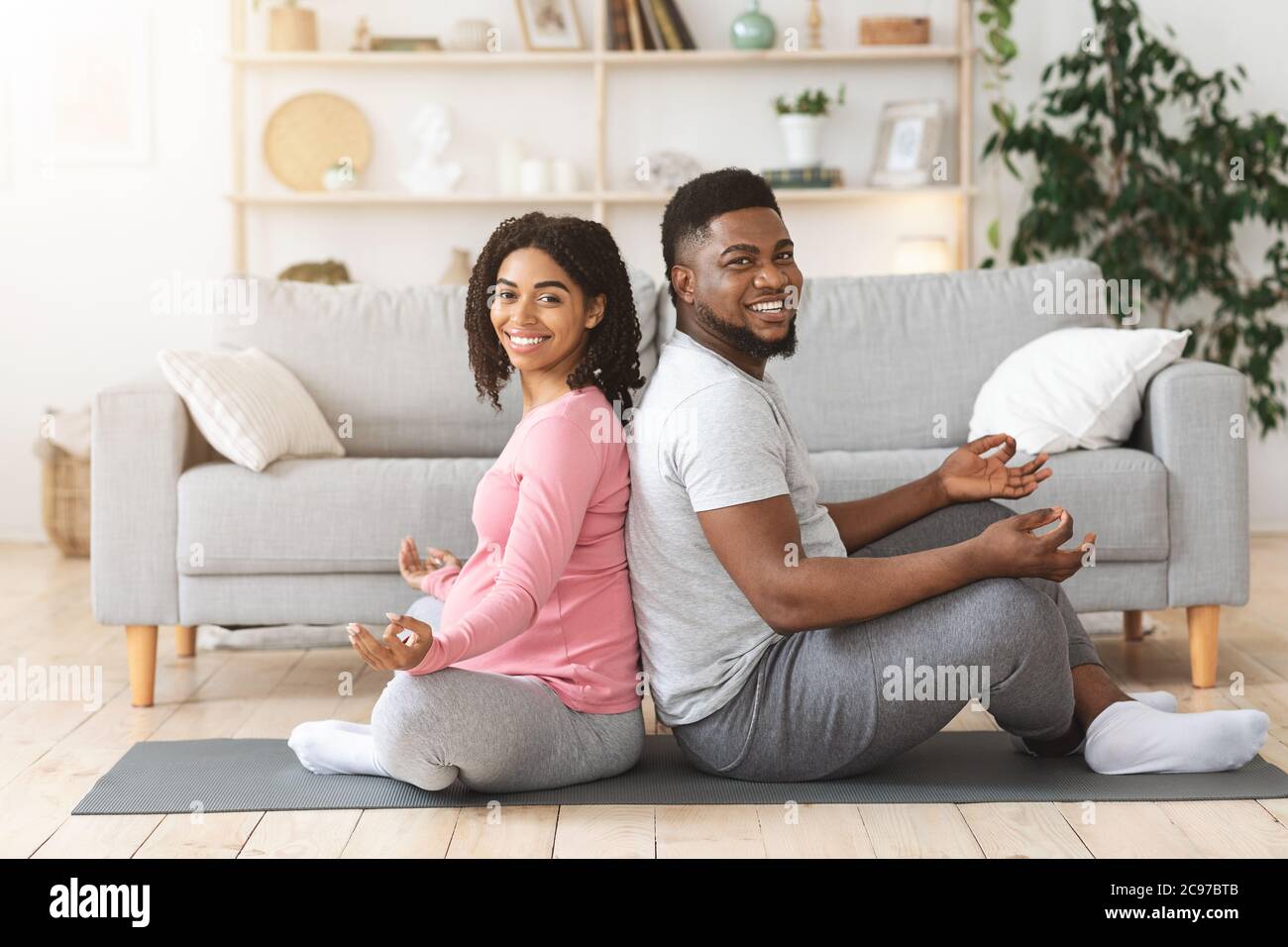 Cheerful african expecting couple exercising together at home Stock Photo