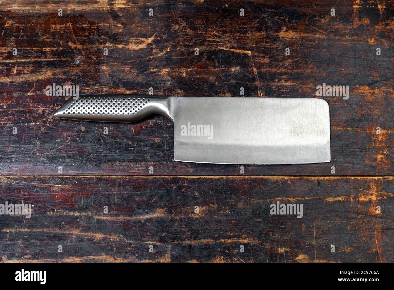 Shiny stainless steel meat cleaver with sharp blade lying on a rustic