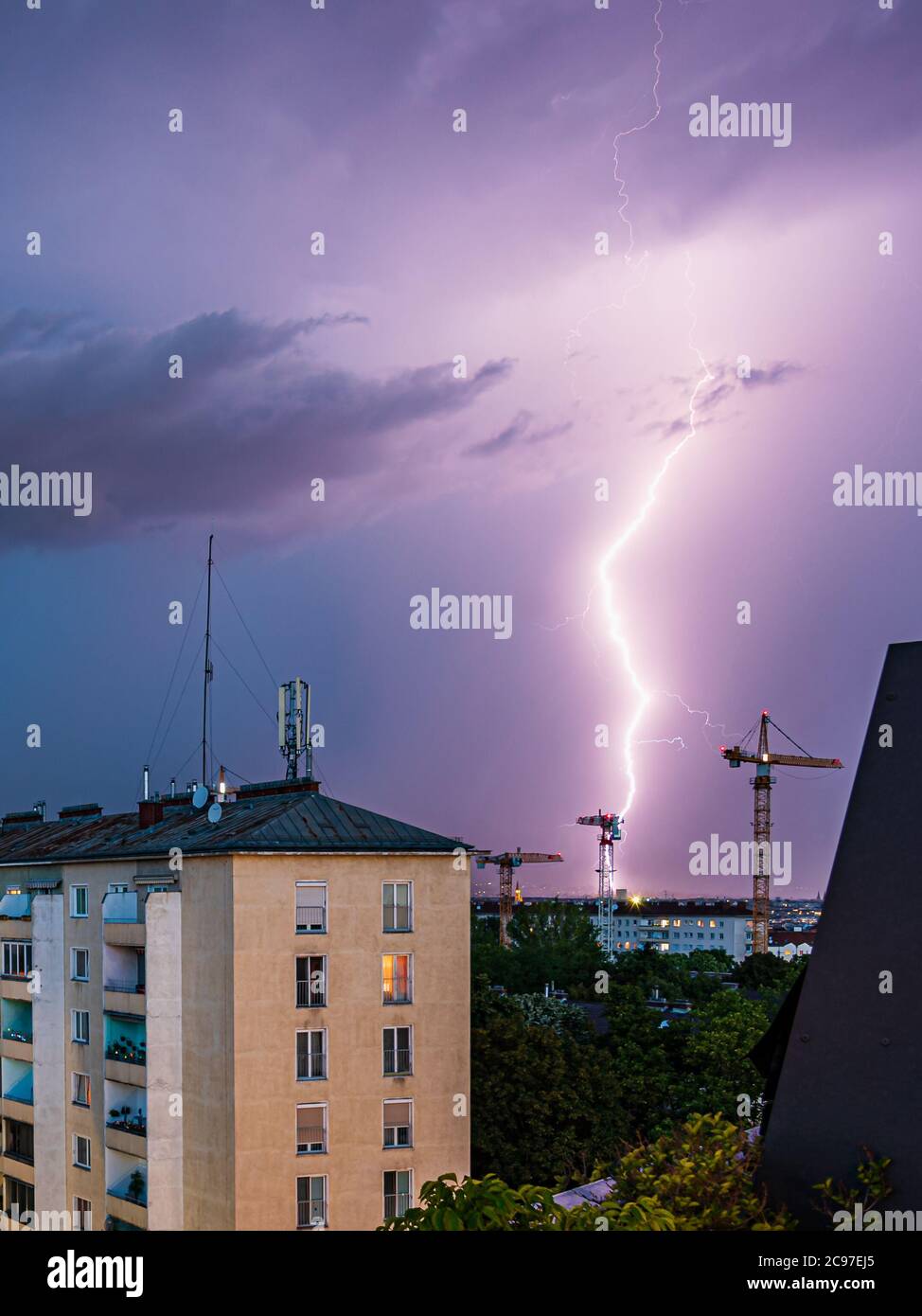 Violent summer thunderstorm with enormous lightning over the Wienerberg City in Vienna with construction cranes on the right side of the picture Stock Photo