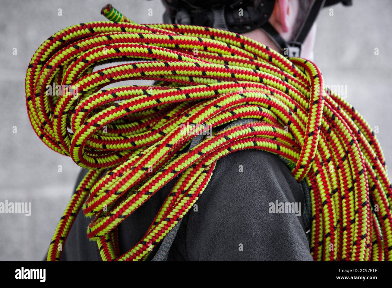An anonymous male with a large reel of claimbing rope over his shoulder ...