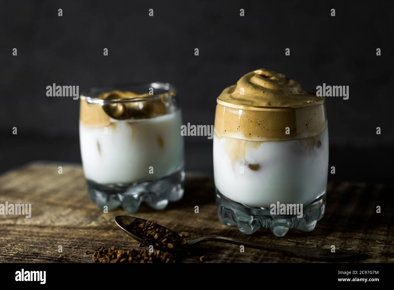 Dalgona Coffee in a transparent cup on a dark background. South Korean drink with whipped instant coffee, sugar and milk. Stock Photo