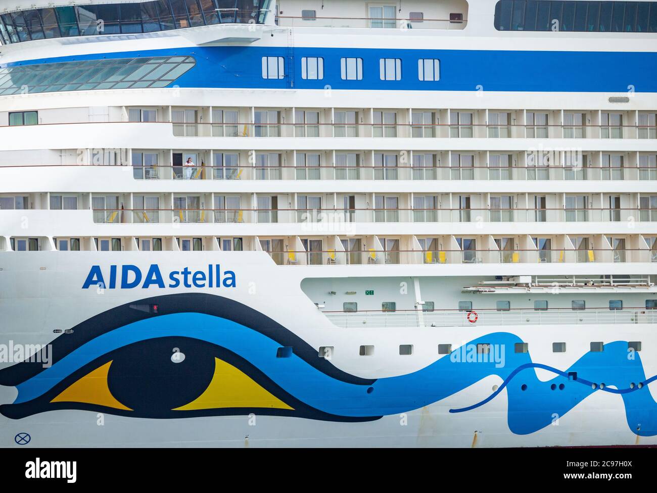 Las Palmas, Gran Canaria, Canary Islands, Spain. 29th July, 2020. A female member of the crew looks out from a cabin of Cruise ship Aida Stella as it docks in Las Palmas on Gran Canaria to take on supplies.The ship, which has stayed anchored off Gran Canaria during the pandemic, has been laid up since the Covid 19 state of emergency in March. There are believed to be more than100,000 crew workers quarantined on cruise ships worldwide. Credit: Alan Dawson/Alamy Live News Stock Photo