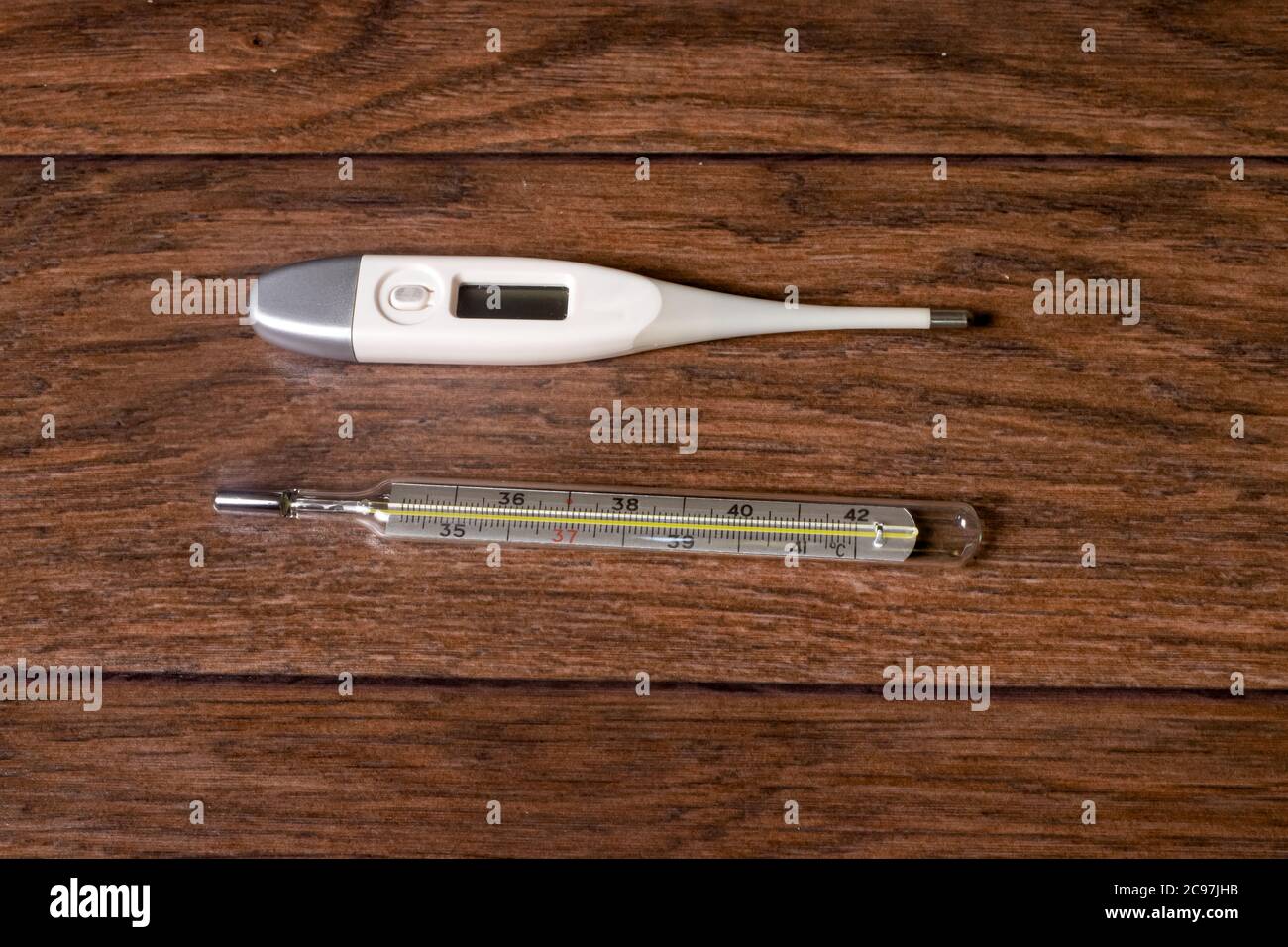 https://c8.alamy.com/comp/2C97JHB/electronic-and-mercury-thermometers-for-measuring-temperature-on-a-brown-wooden-background-a-method-for-diagnosing-fever-2C97JHB.jpg