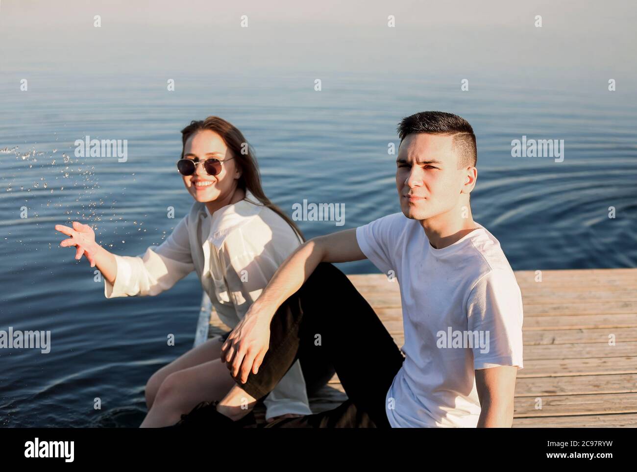 Young happy girlfriend and boyfriend on wooden quay and looking at each ...