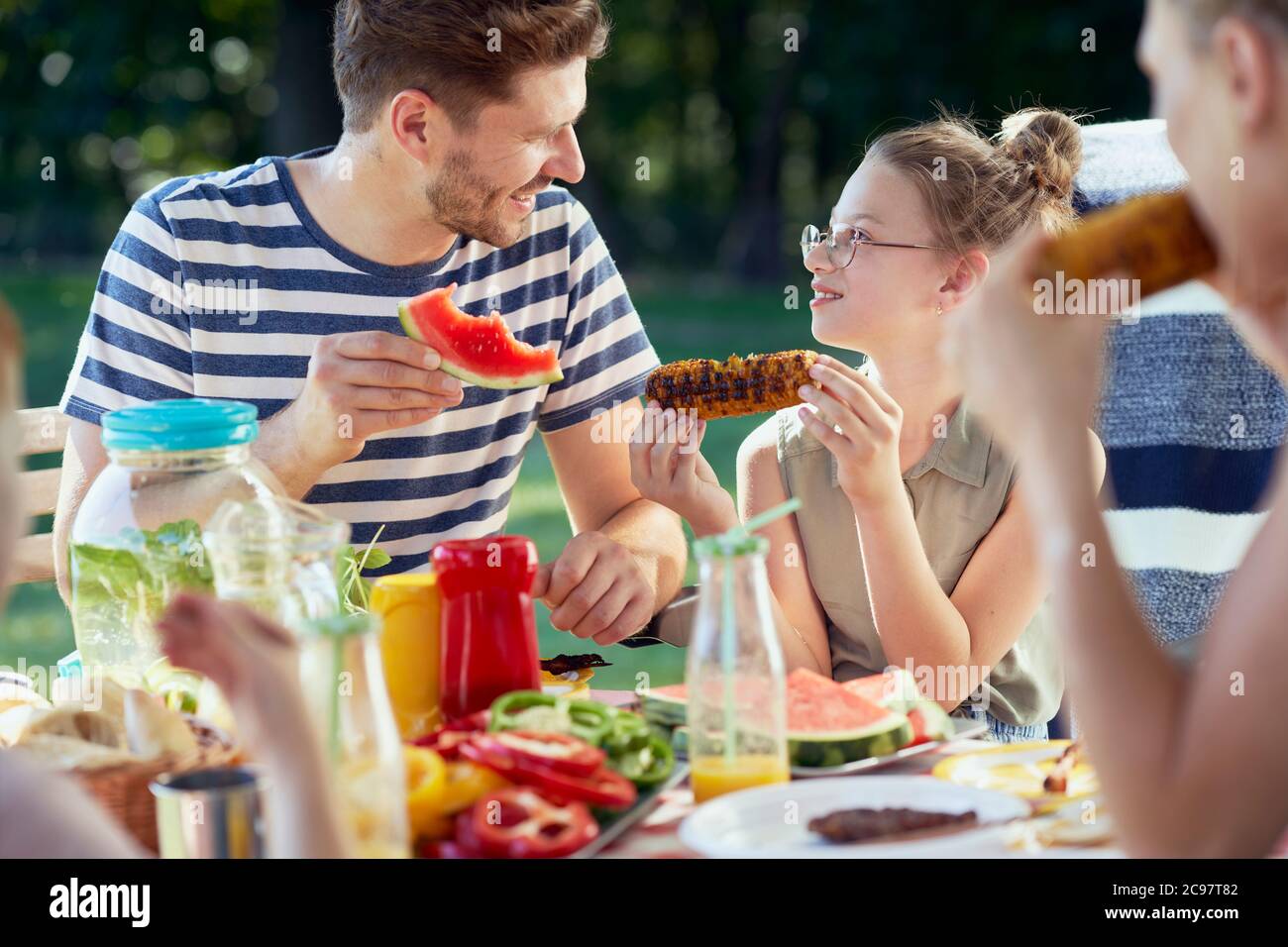 Family sitting at table and eating grilled food Stock Photo