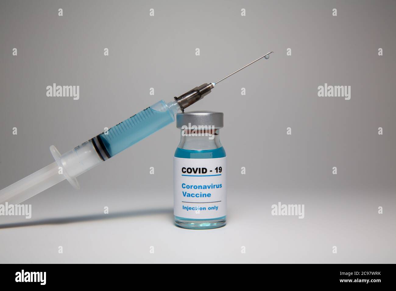 Small vaccine bottle (phial) with a label that reads 'Covid - 19 Corona virus Vaccine injection only' and a medical syringe injection with a vaccine d Stock Photo