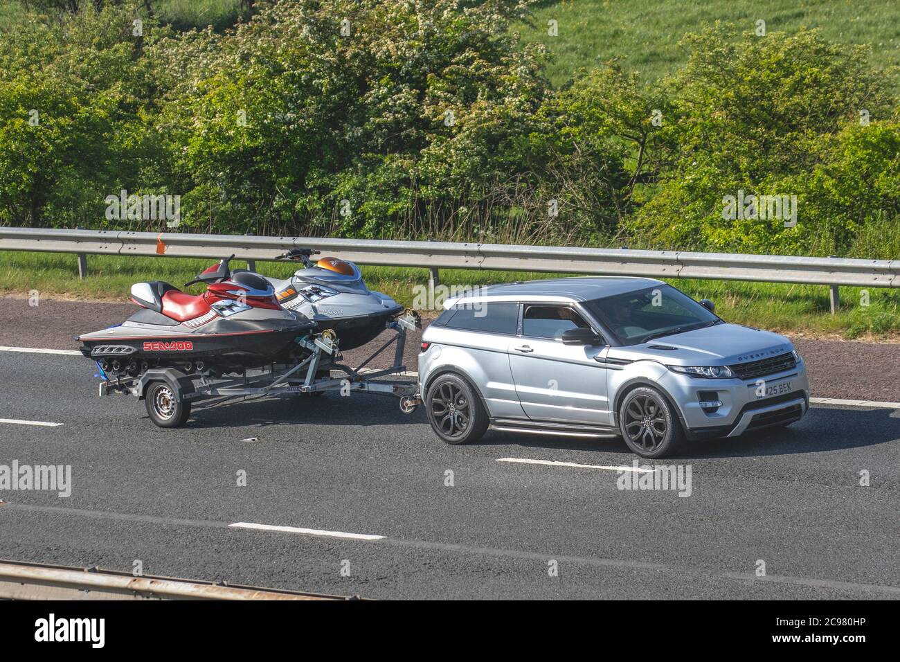 2011 Land Rover Range Rover Evoque Dynamic towing double Sea-Doo personal watercraft Jet Ski trailer; Vehicular traffic moving vehicles, cars driving vehicle on UK roads, motors, motoring on the M6 motorway highway network. Stock Photo