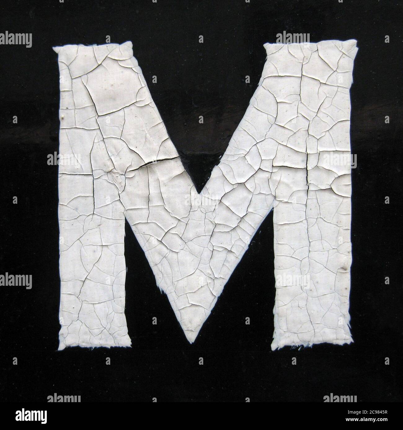 A Close Up Of The Letter M Hand Painted In White Paint On A Black Painted Background Stock Photo