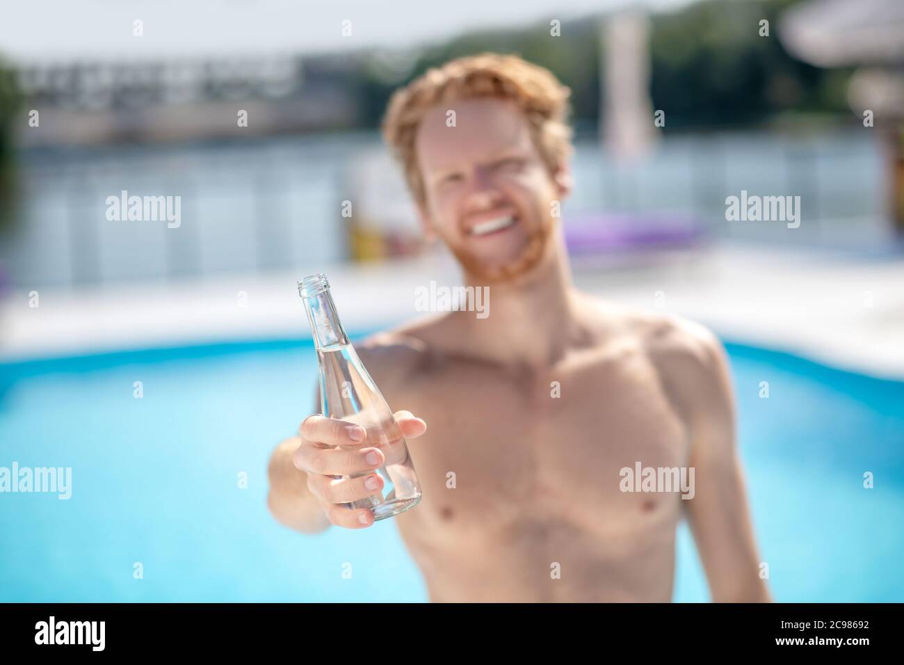 Bottle of drinking water in mans outstretched hand. Stock Photo
