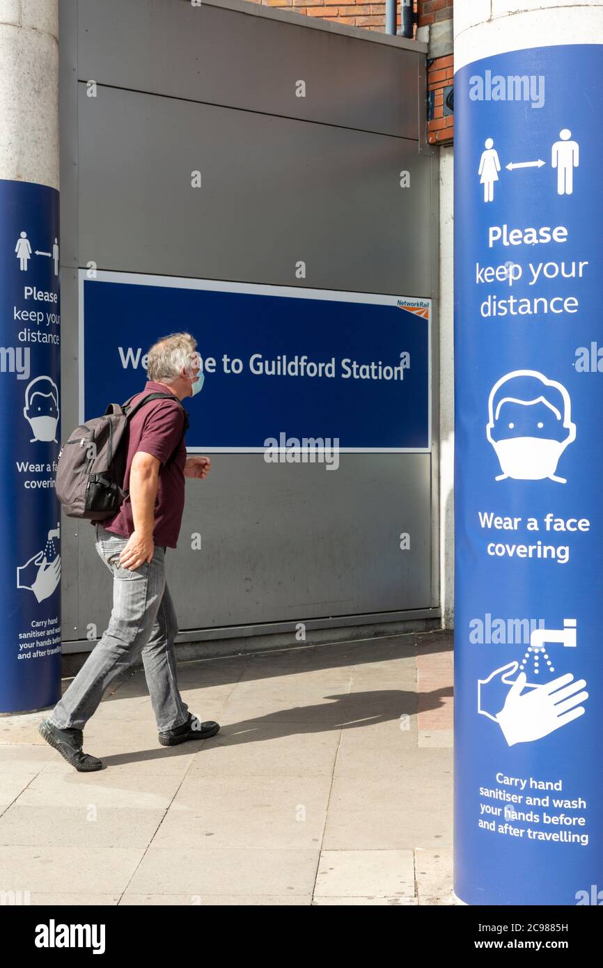 A man entering Guildford train station between COVID-19 signage, Surrey, England, 29 July 2020 Stock Photo