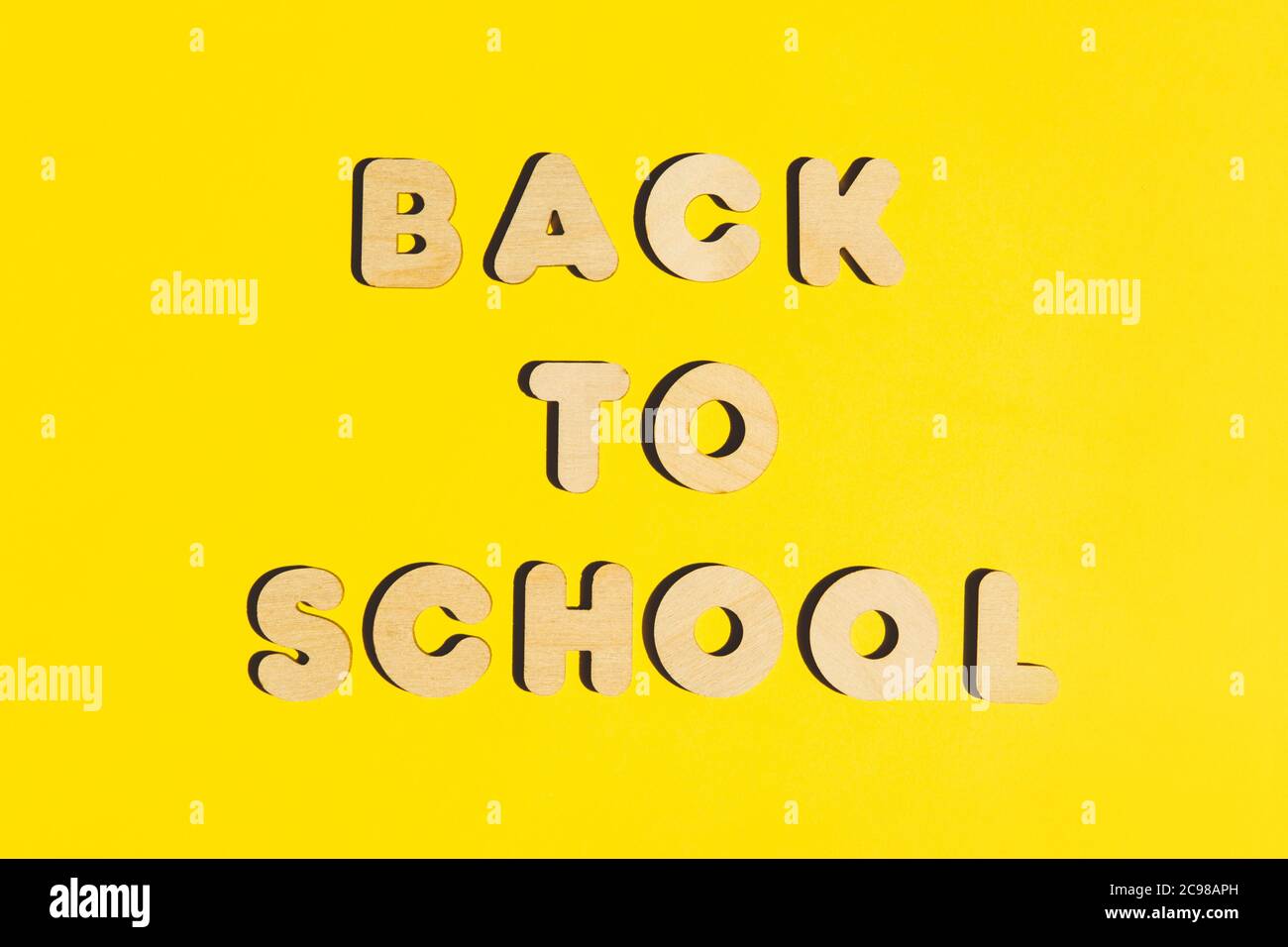 Words Back to School from wooden letters on a yellow background. Back to school concept. Flat lay. Stock Photo