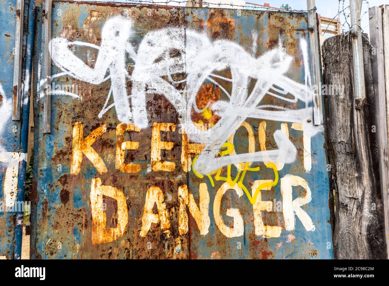 Danger keep out rough painted sign on decaying rusty metal gates in