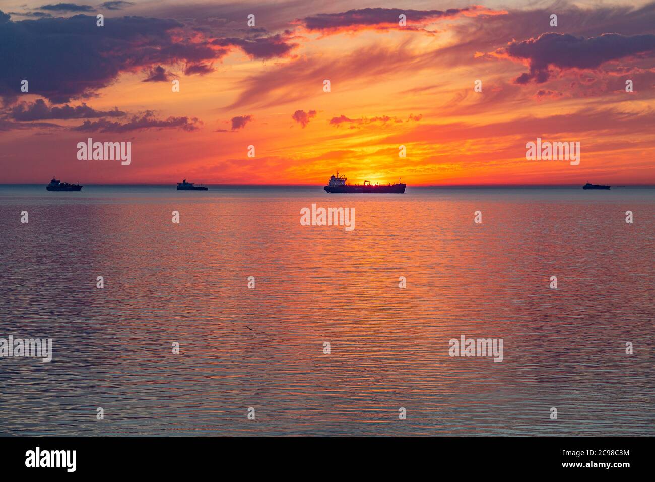 Sunset and clouds at sea with ships in the background Stock Photo - Alamy