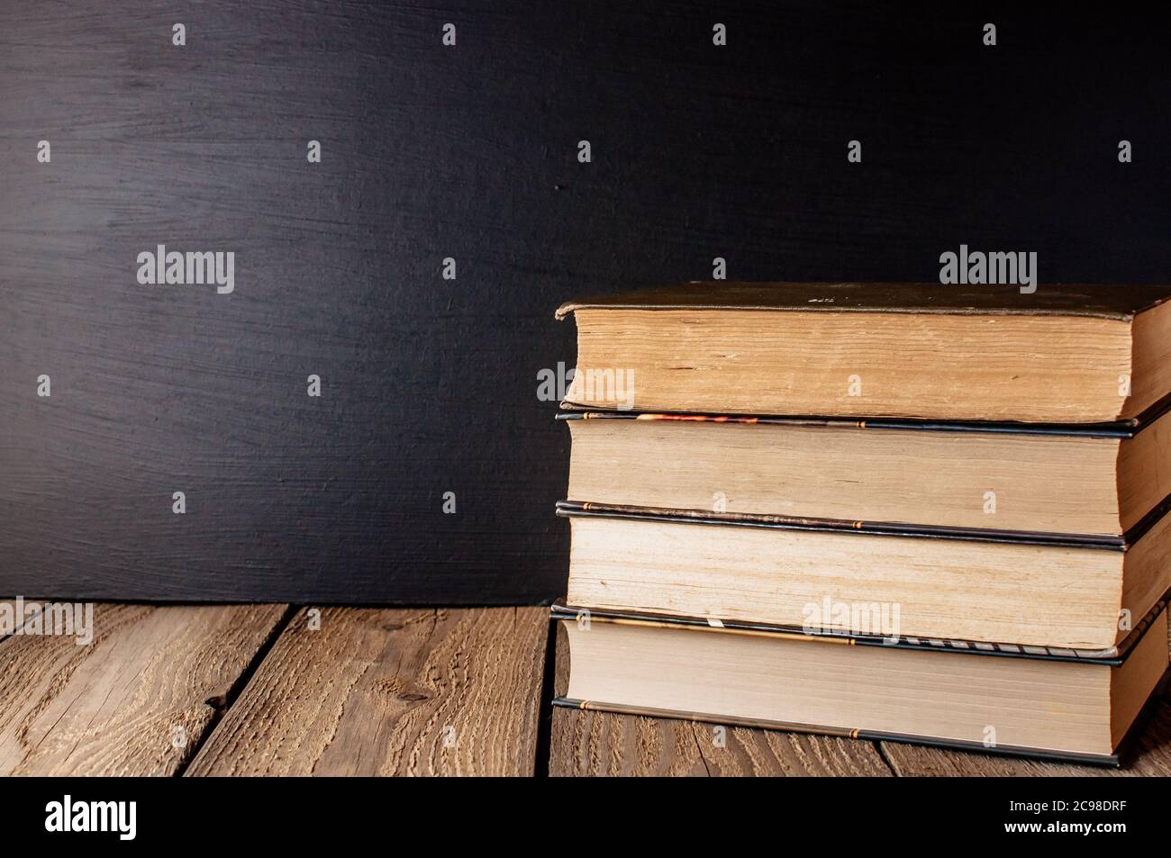 books stacked on a wooden table in a rustic style on the background a school blackboard. The concept of welcome back to school. copy space Stock Photo