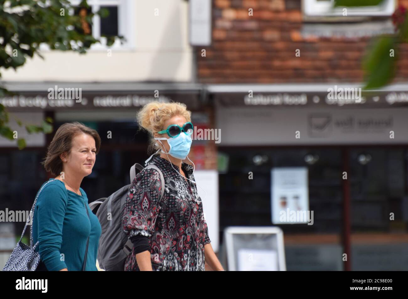 A mother and daughter out shopping in a British Town during the Covid 19 pandemic - he daughter wears a face mask Stock Photo