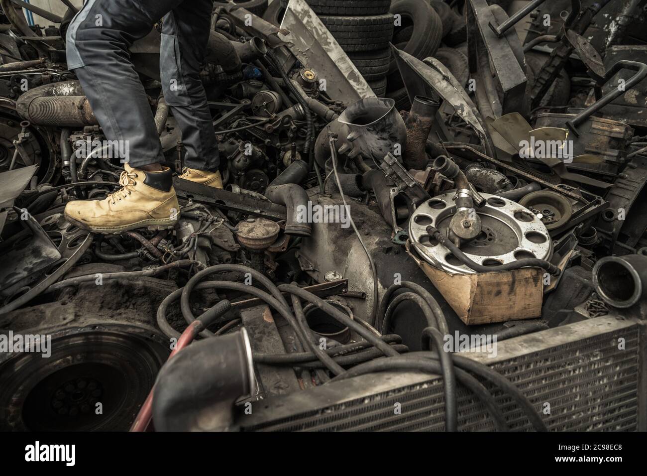 Hoarder Auto Service Worker Walking on a Pile of Automotive Waste and Used Parts. Transportation Industry Theme. Stock Photo