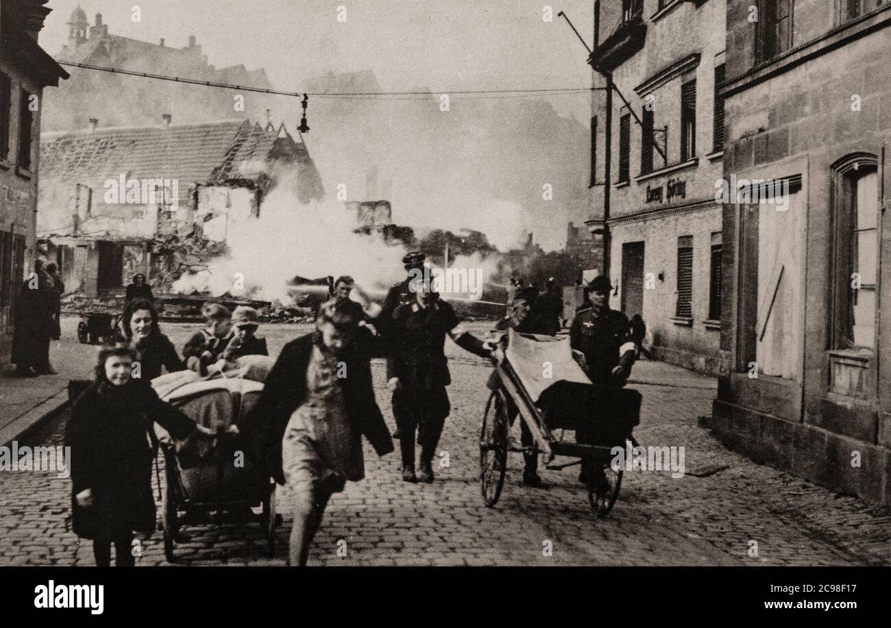 Local people leave their town of Kronach in Upper Franconia, Germany, as the US 11th Armoured Division move in as World War Two grinds to an end in 1945. Stock Photo