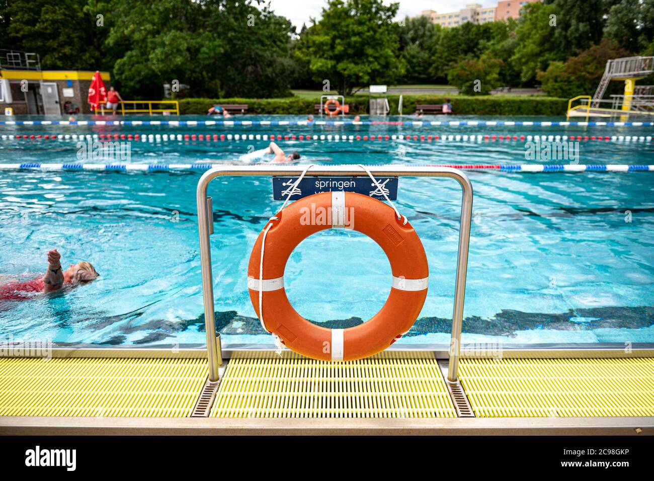 29 July 2020, Berlin: Visitors swim through the swimmer's pool of the Gropiusstadt combined swimming pool past a life ring. Photo: Fabian Sommer/dpa Stock Photo