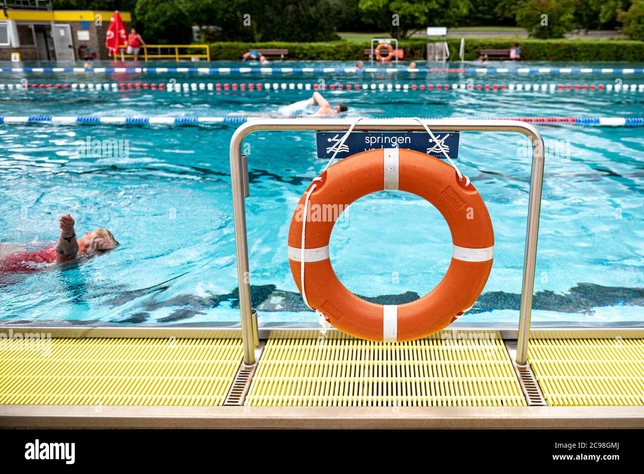 29 July 2020, Berlin: Visitors swim through the swimmer's pool of the Gropiusstadt combined swimming pool past a life ring. Photo: Fabian Sommer/dpa Stock Photo
