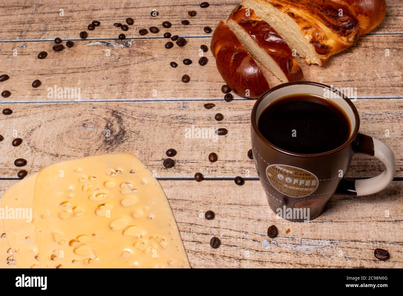 The idea of a delicious breakfast for the whole family. Wicker bun, cheese and aromatic black coffee. Stock Photo