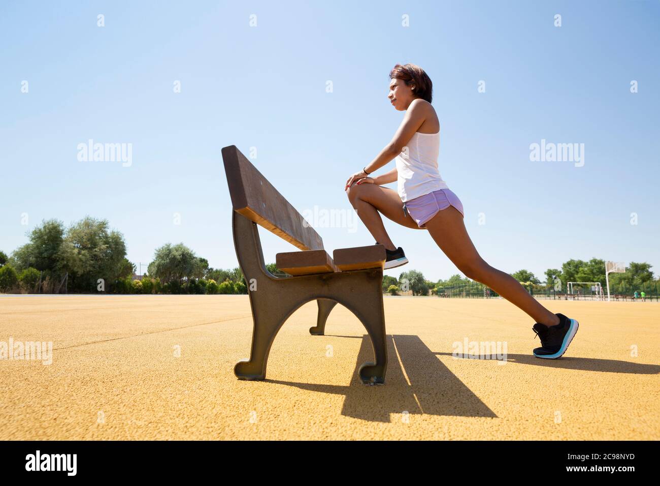 Young woman stretching her muscles on an outdoor bench before doing sport. Space for text. Stock Photo