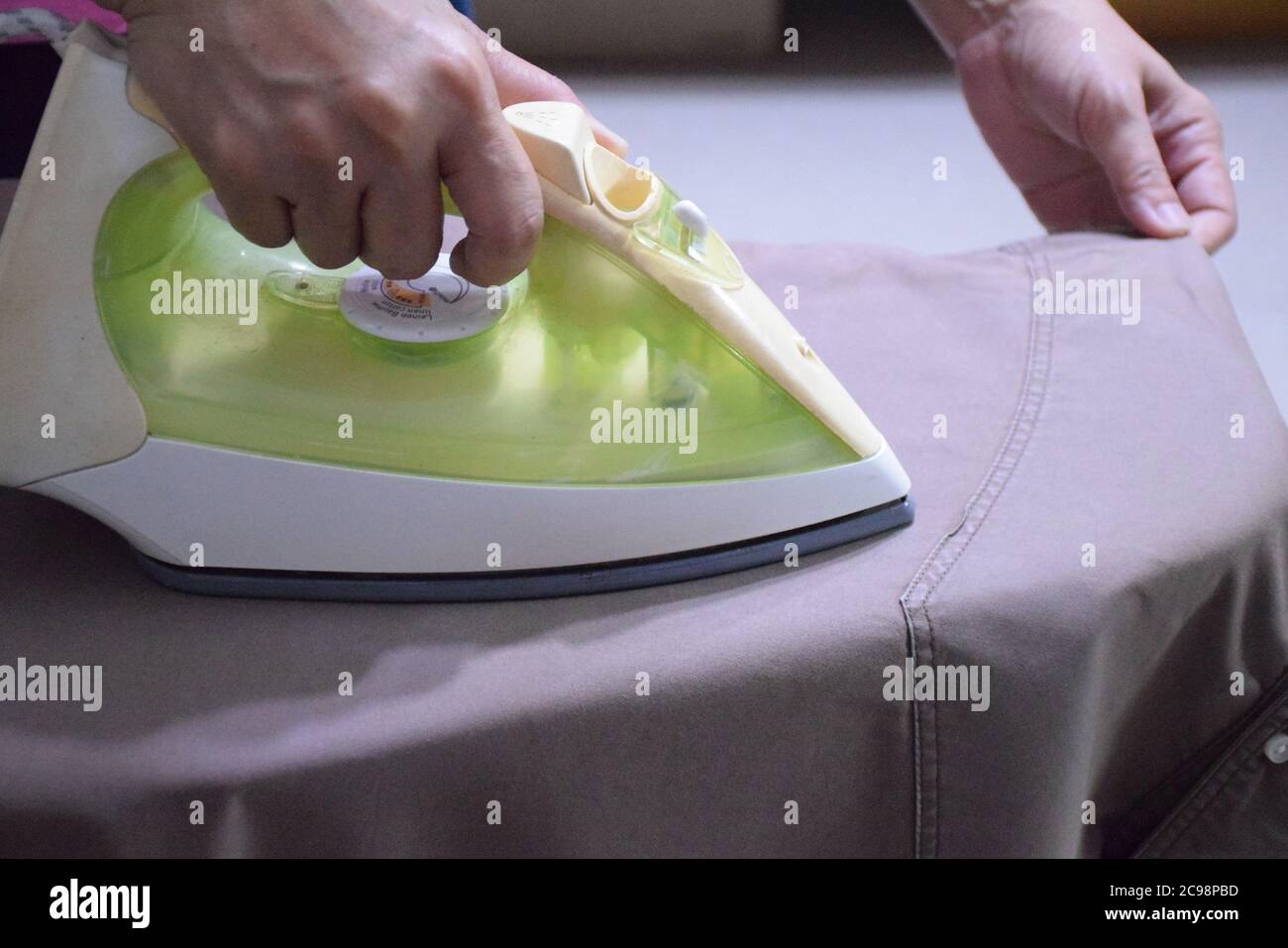 Mom hands holding Electric steam iron , steaming clothes,shallow depth of field Stock Photo