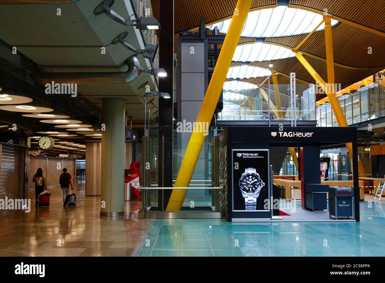 28th July 2020, Barajas Airport, Madrid, Spain: Passengers walk through the near empy departure lounge area of the Terminal 4S building of Barajas Airport. Reduced numbers of flights are now operating between European countries after the lockdown to control the covid-19 coronavirus, and governments have put a system of air bridges in place to facilitate travel and tourism. Spain has seen a number of new outbreaks in recent days, prompting the UK government to announce that people returning to the UK from Spain should quarantine for 14 days on arrival. Stock Photo