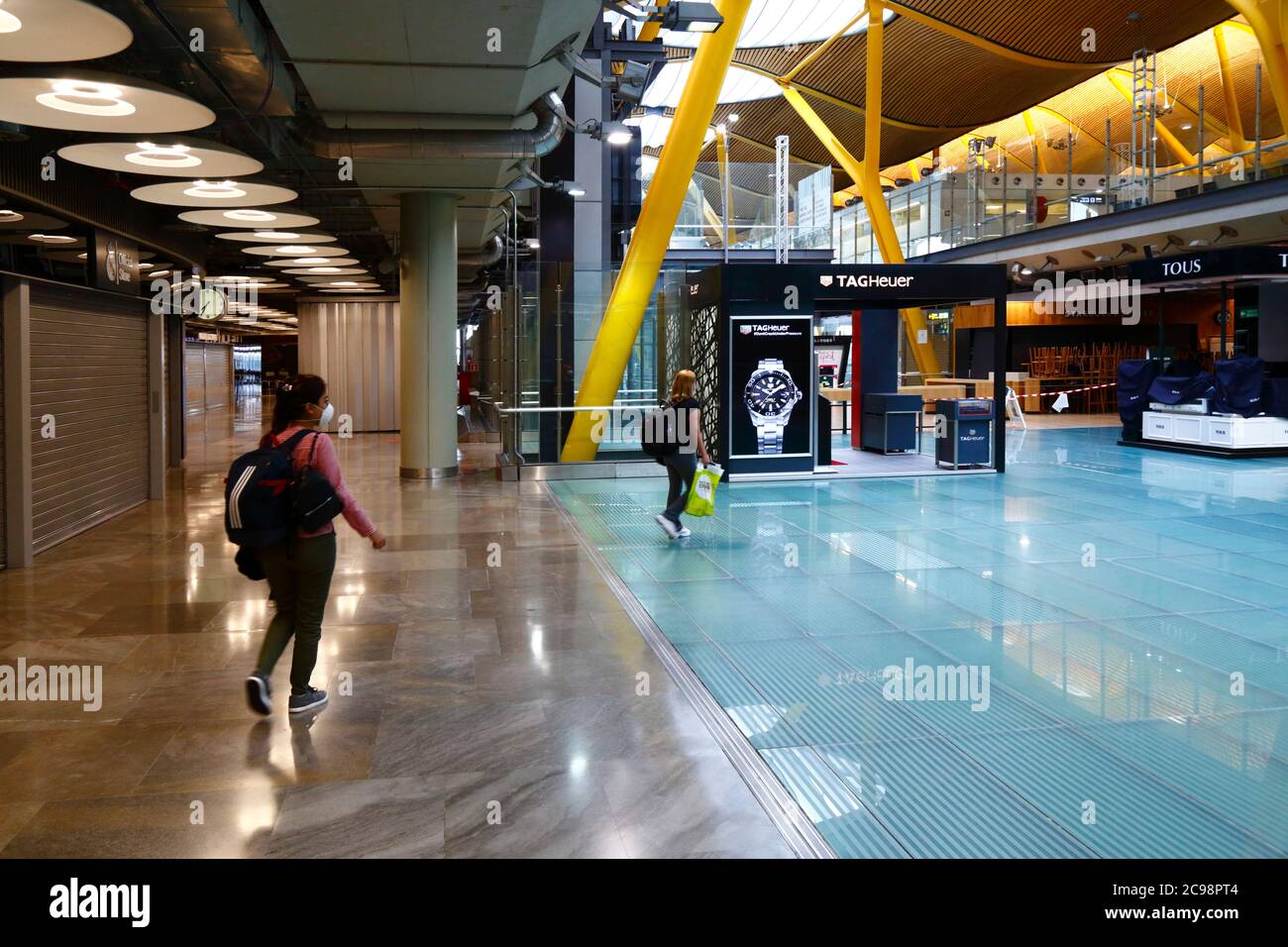 28th July 2020, Barajas Airport, Madrid, Spain: Passengers walk through the near empy departure lounge area of the Terminal 4S building of Barajas Airport. Reduced numbers of flights are now operating between European countries after the lockdown to control the covid-19 coronavirus, and governments have put a system of air bridges in place to facilitate travel and tourism. Spain has seen a number of new outbreaks in recent days, prompting the UK government to announce that people returning to the UK from Spain should quarantine for 14 days on arrival. Stock Photo