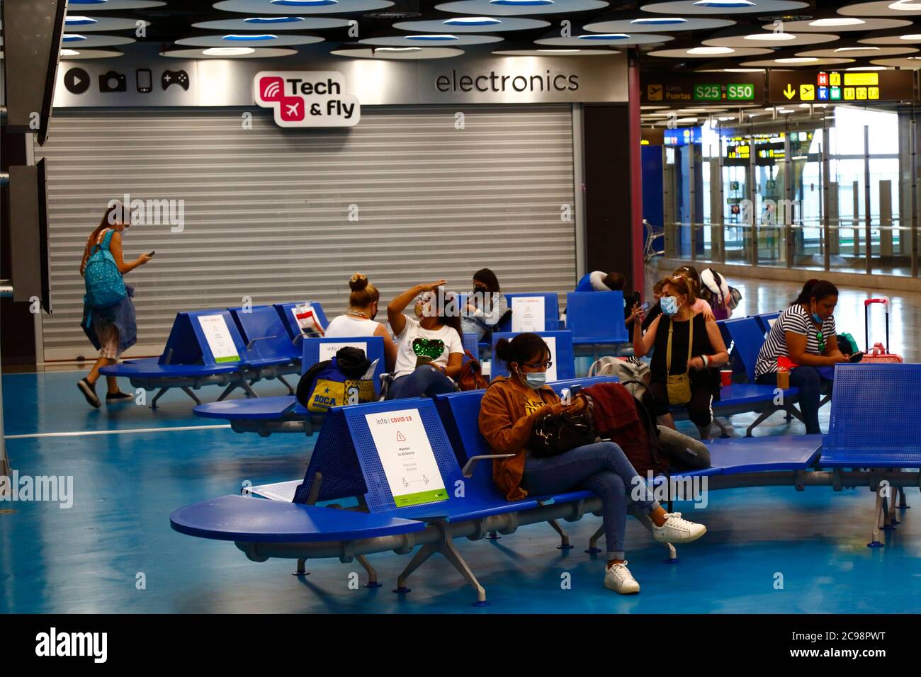 28th July 2020, Barajas Airport, Madrid, Spain: Passengers social distancing in the near empy departure lounge area of the Terminal 4S building of Barajas Airport. Reduced numbers of flights are now operating between European countries after the lockdown to control the covid-19 coronavirus, and governments have put a system of air bridges in place to facilitate travel and tourism. Spain has seen a number of new outbreaks in recent days, prompting the UK government to announce that people returning to the UK from Spain should quarantine for 14 days on arrival. Stock Photo
