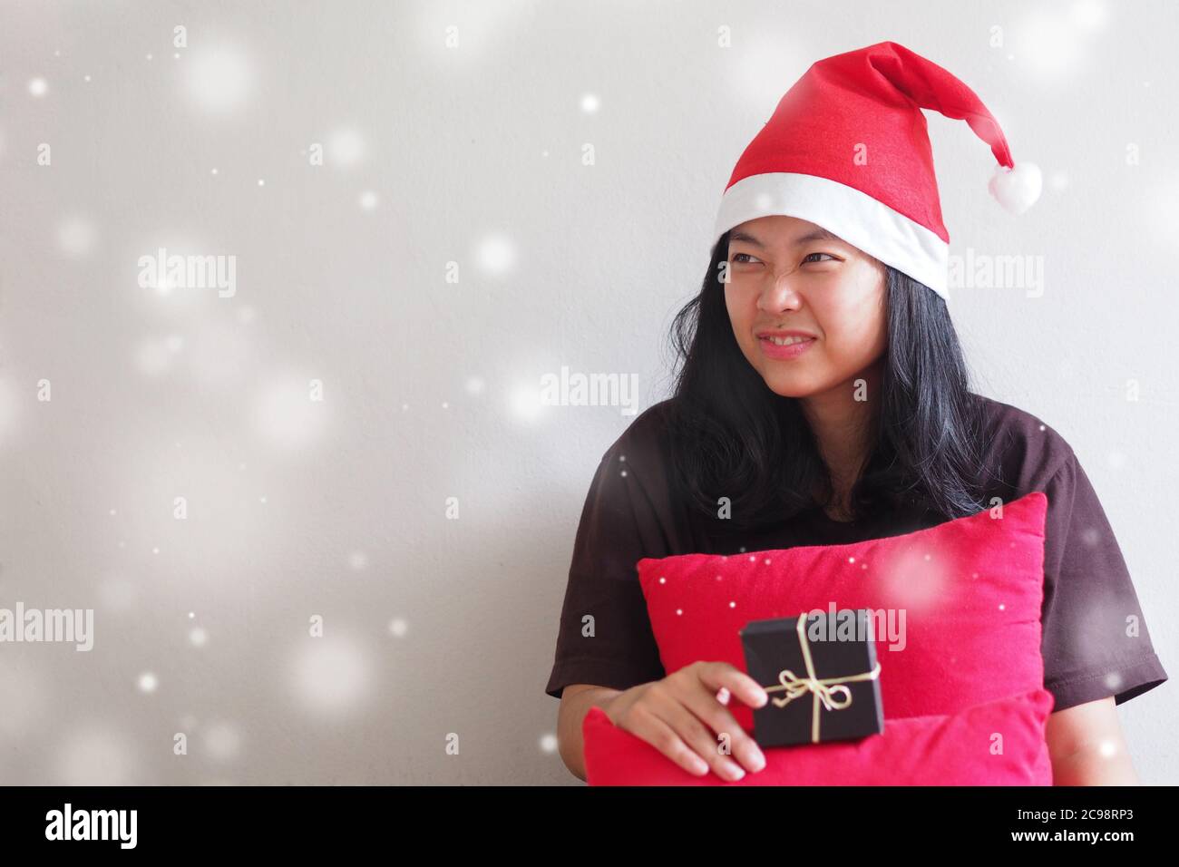 Young Woman wearing a Santa hat and sitting, waiting for the gift with Snow scene and Copy space. Stock Photo