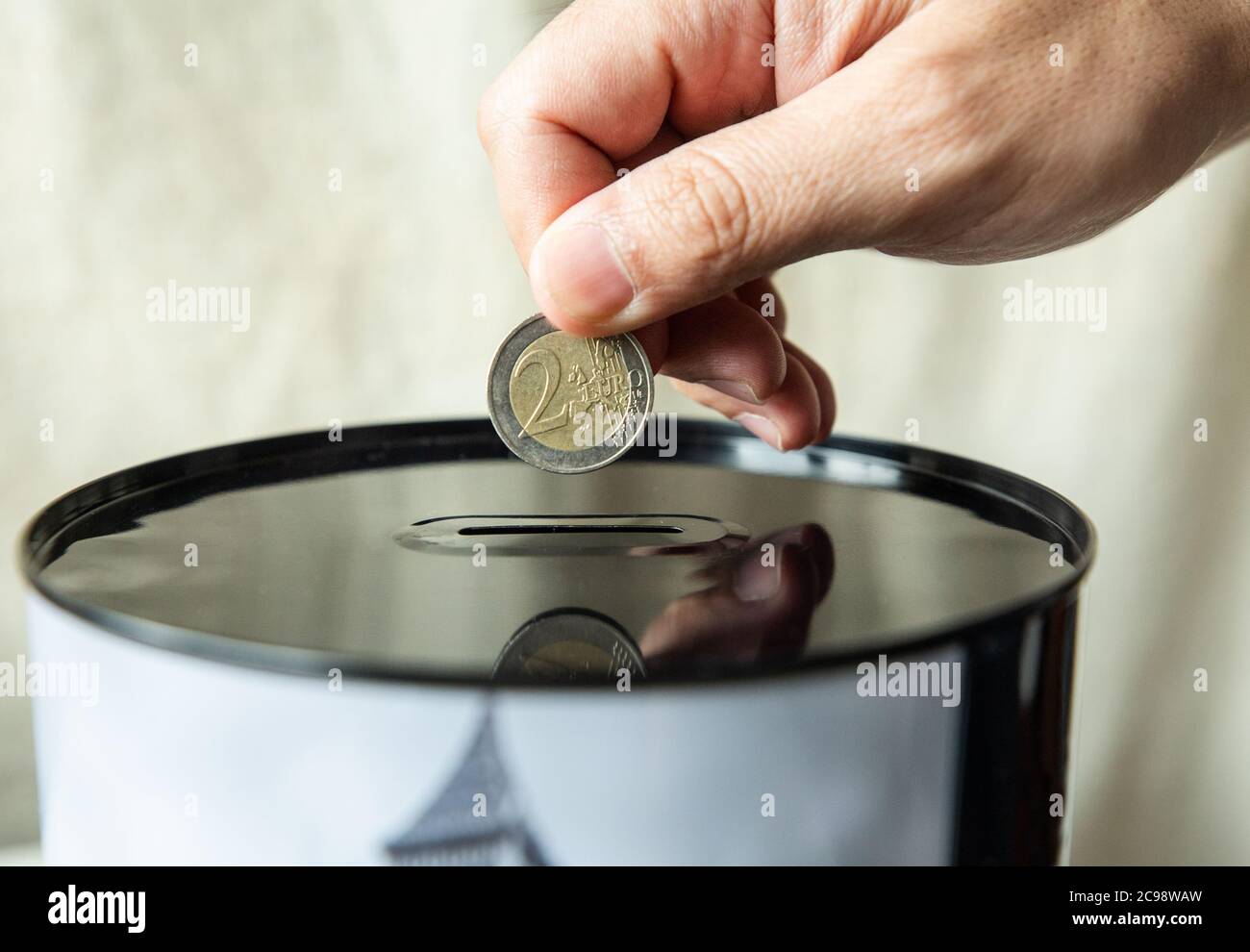 hand puts a 2 euro coin in a piggy bank Stock Photo - Alamy