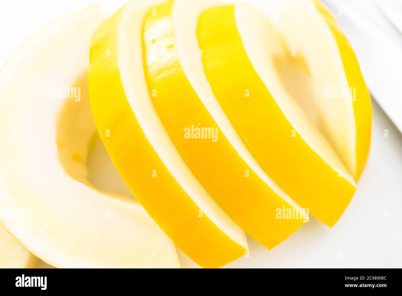 Slicong golden dewlicious melon on a white cutting board Stock Photo Alamy