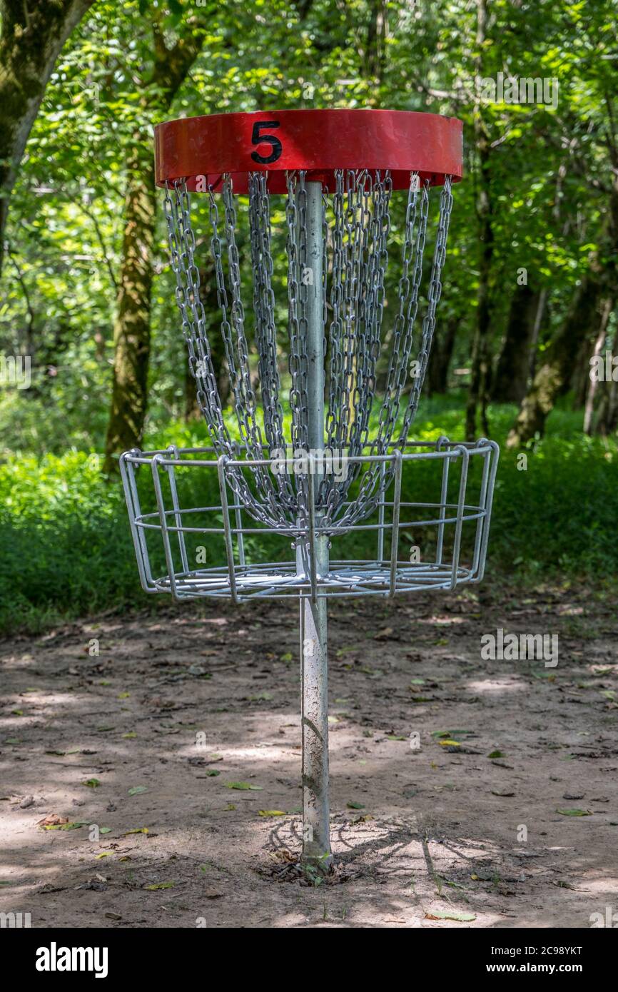 A red #5 disc golf basket empty in the woodlands on a course in the park in  the shade on a sunny day in summertime closeup Stock Photo - Alamy