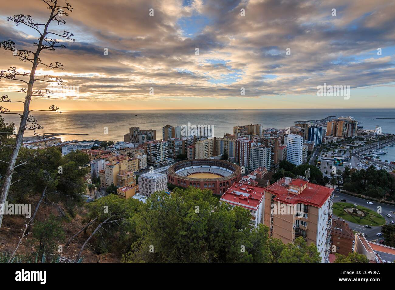 Spanish coast in Andalusia in the morning. View over the city of Malaga at sunrise with clouds and an orange horizon. City view on the Costa del Sol f Stock Photo