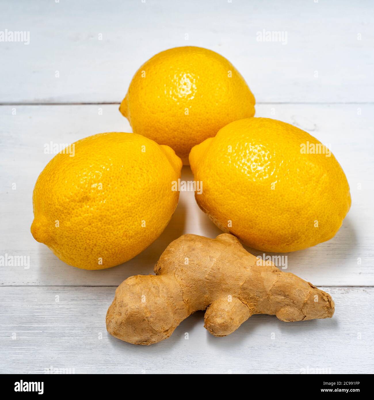 three lemons and ginger root on white wooden background Stock Photo