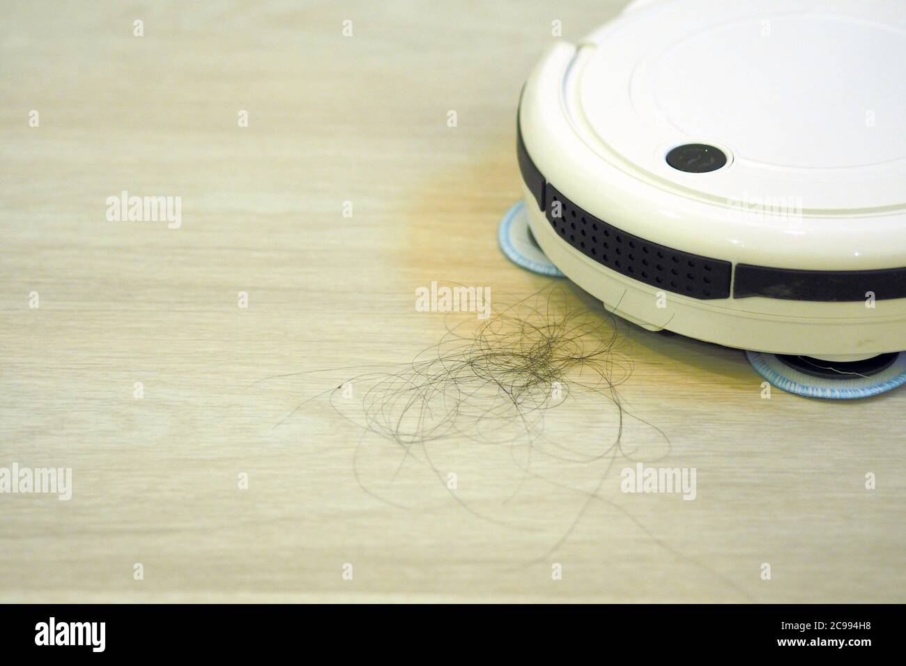 The robot vacuum cleaner is cleaning floor. Stock Photo