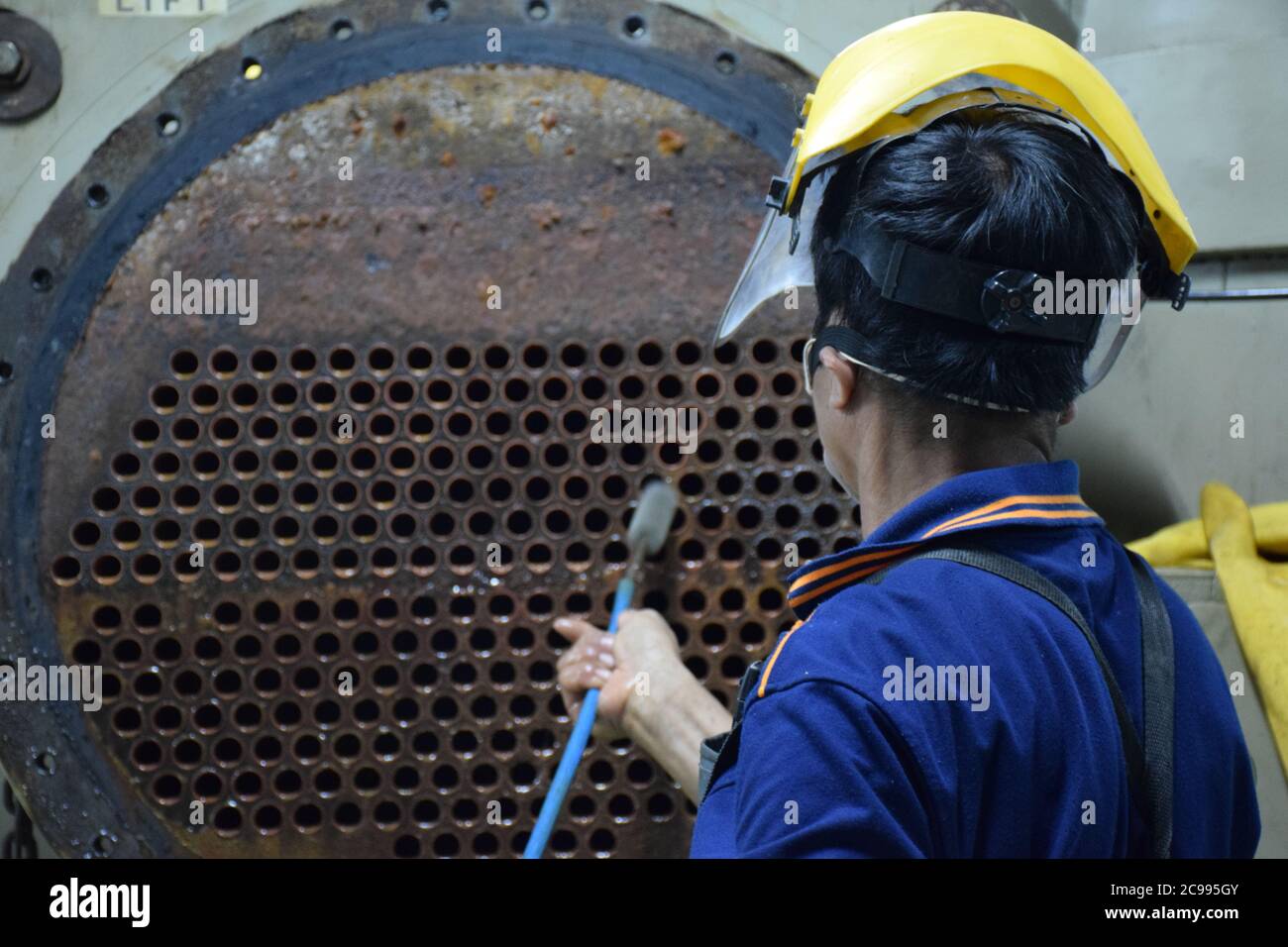 Mechanic is using brush to clean condenser tube of Chiller - HVAC System. Stock Photo
