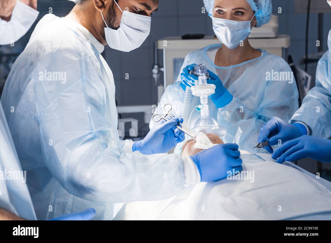 Pre oxygenation for general anesthesia. Surgery equipment, doctors in uniform and scrub cap on head being ready for operating Stock Photo