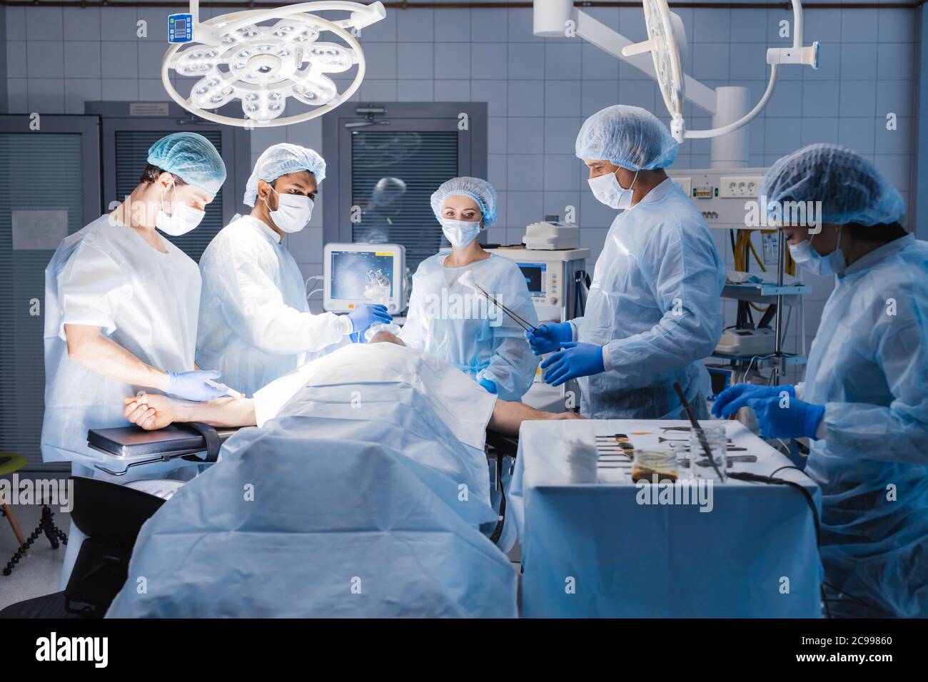 Medical team preparing equipment for surgery in operation room. Stock Photo