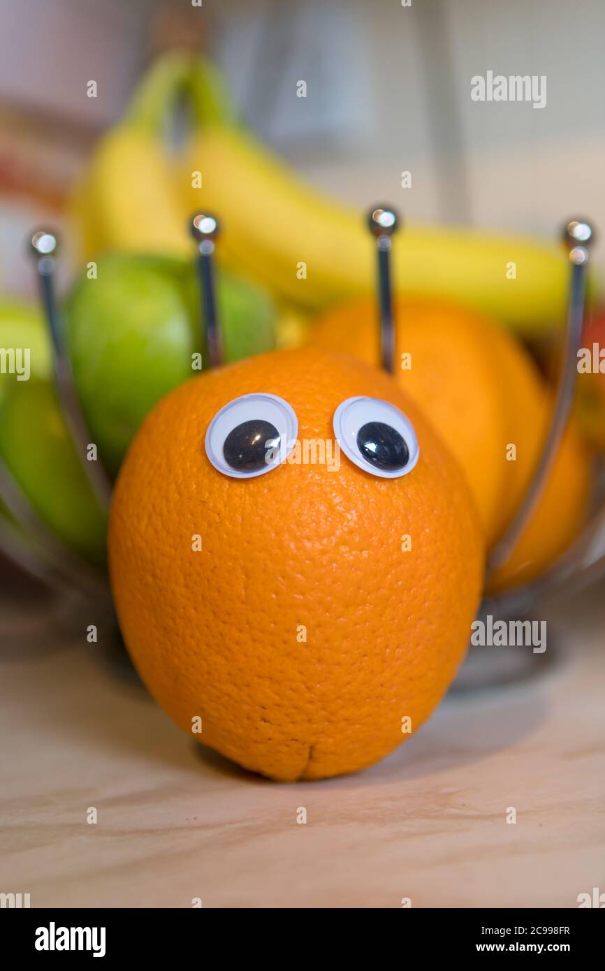 Orange in the fruit bowl with bobbly eyes. Funny face Stock Photo
